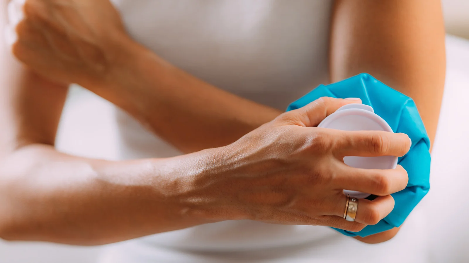 Elbow Pain Treatment. Woman Holding An Ice Bag Compress On A Painful Elbow